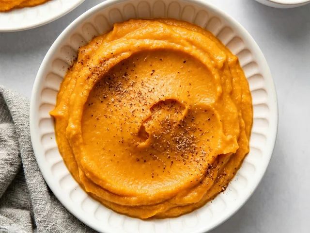 Purée de patate douce crémeuse dans un bol blanc, vue de dessus avec muscade râpée